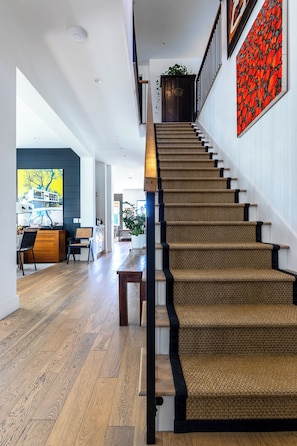 Eine Treppe mit gewebtem Teppich, Holzsitzstufen und schwarzen Geländern.