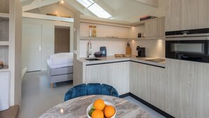 A modern kitchen with a built-in oven, a dining area with a marble table, and a cozy sleeping area with a bed. - Lepelaar by Interhome (Domburg)