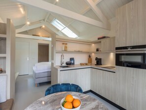 A modern kitchen with a built-in oven, a dining area with a marble table, and a cozy sleeping area with a bed. - Lepelaar by Interhome (Domburg)
