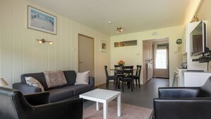 A living room with a sofa, a coffee table, and a dining area with chairs and a table. - Duingras by Interhome (Vlissingen)