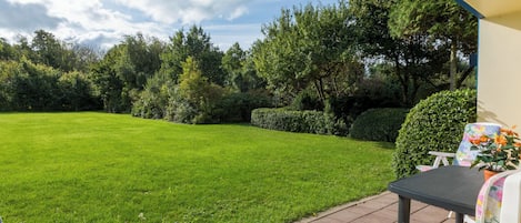 A patio with a lawn, a table, and two chairs.