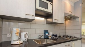 A modern kitchen with a microwave, kettle, gas stove, and a sink. - Duingras by Interhome (Vlissingen)