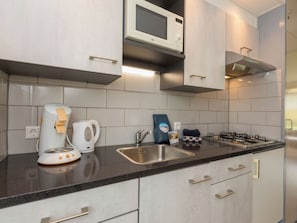 A modern kitchen with a microwave, kettle, gas stove, and a sink. - Duingras by Interhome (Vlissingen)