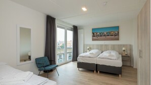 Una camera d'albergo con un letto, una sedia, una scrivania, un quadro e vista dalla finestra.