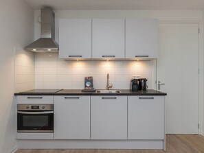 Eine moderne Küche mit weißen Schränken, einer schwarzen Arbeitsplatte, einem Einbauofen, einer Dunstabzugshaube und einer Kaffeemaschine.