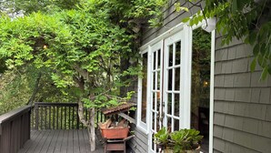 A wooden deck with a railing, a potted plant, and a barrel.