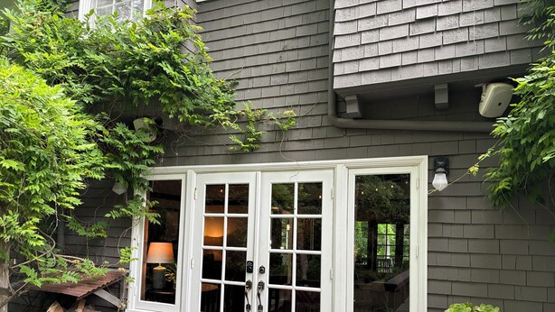 A house with a white front door, a wooden deck, and a potted plant on the side.