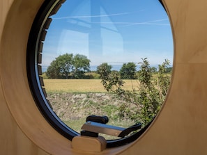A window with a view of a field, trees, and a distant landscape. - Tiny House Rustepolder by Interhome (Vrouwenpolder)
