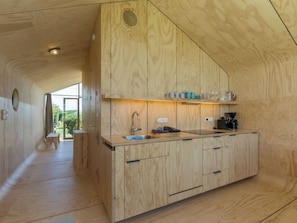 A wooden interior with a kitchen area, including cabinets, a sink, and a coffee machine. - Tiny House Rustepolder by Interhome (Vrouwenpolder)