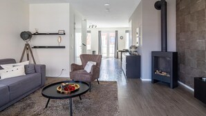 Un salon moderne avec un canapé, un fauteuil, une table basse et une cheminée.