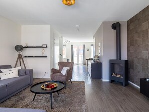 Ein modernes Wohnzimmer mit einer Couch, einem Sessel, einem Couchtisch und einem Kamin.