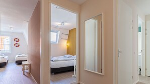 Ein Schlafzimmer mit einem Bett, einem Nachttisch, einem Spiegel und einem Fenster.