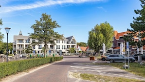 Eine gepflasterte Straße mit Zebrastreifen, parkenden Autos und Gebäuden mit Balkonen.