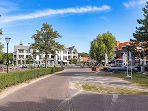 Eine gepflasterte Straße mit Zebrastreifen, parkenden Autos und Gebäuden mit Balkonen.