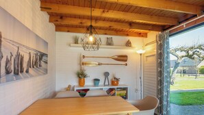 Een eethoek met een houten tafel en stoelen, een hanglamp en uitzicht op de omgeving.