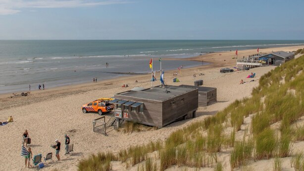 Een strand met een bewakingspost, strandstoelen en een buggy.