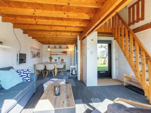 A cozy interior with a wooden ceiling, a sofa, a dining area, and a staircase. - Zeenatuur by Interhome (Burgh-Haamstede)