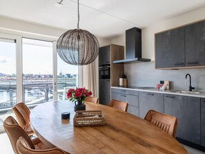 Une cuisine moderne avec un coin repas, de grandes fenêtres et une vue sur le paysage urbain.