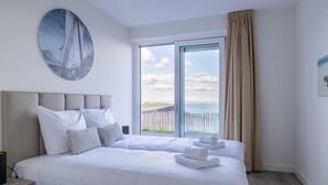 Ein Hotelzimmer mit einem großen Bett, Meerblick und einem Bild an der Wand.