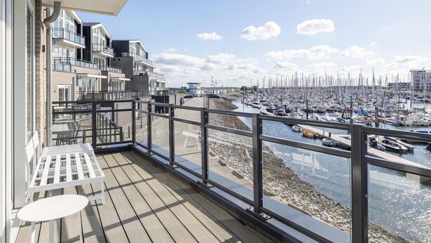 Ein Balkon mit Blick auf eine Marina, ein mehrstöckiges Gebäude und ein klarer Himmel.