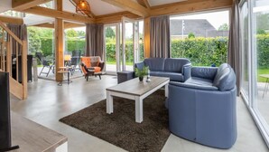 Un vaste espace de vie comprenant un canapé, une table basse et une table à manger. De grandes fenêtres offrent une vue sur l’extérieur.