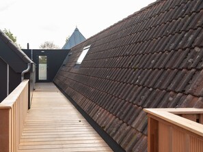A rooftop with a wooden deck, a sloped roof, and a small window. - Bomont ZonStrand by Interhome (Renesse)