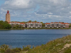 A waterfront property with a prominent tower, multiple-story buildings with balconies, and a body of water. - ZuidLicht by Interhome (Westkapelle)