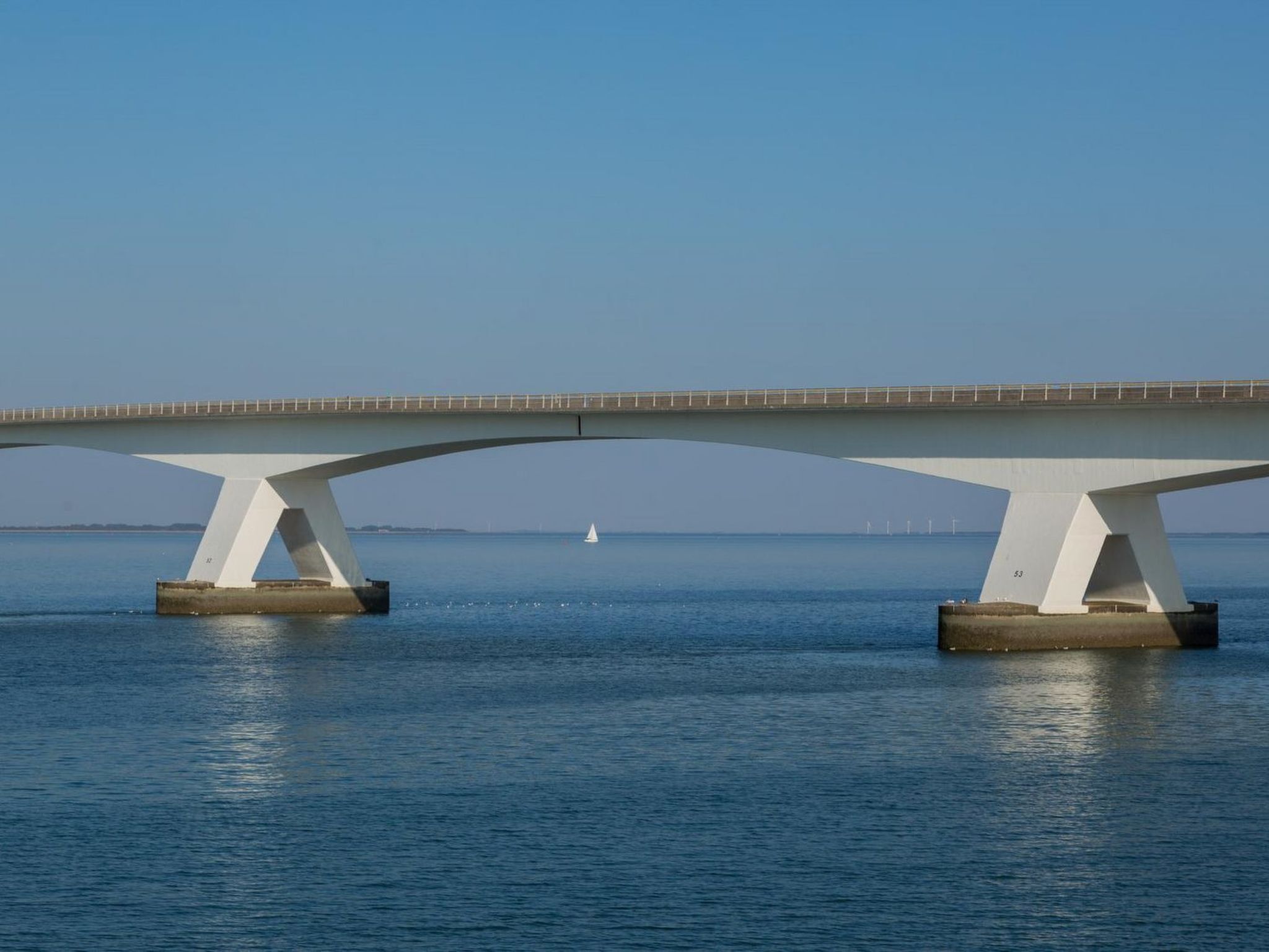 A bridge with a white structure over a body of water.