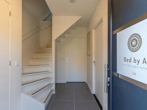 Ein Flur mit Treppe, einer Tür mit einem Logo und einem Fliesenboden.