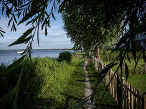 A pathway leading to a body of water, surrounded by greenery and a wooden fence. - LagoLux Sneekermeer by Interhome (Offingawier)