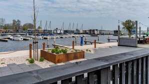 Un puerto deportivo con barcos amarrados, una cubierta de madera y un pequeño jardín.