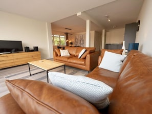 A modern living room with a leather sofa, a coffee table, and a TV on a wooden cabinet. - LagoLux Sneekermeer by Interhome (Offingawier)