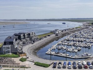 A marina with boats, a parking area, and a building with a modern design. - Aurum Solis by Interhome (Sint-Annaland)
