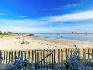 A beach with a wooden fence, a sandy shore, and a calm body of water. - Aurum Solis by Interhome (Sint-Annaland)