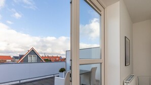 Ein moderner Balkon mit weißem Stuhl, kleinem Tisch und Heizkörper.