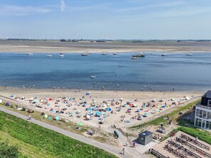 Ein Strand mit Booten, Sonnenschirmen und Menschen.