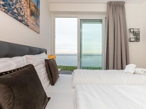 Ein Hotelzimmer mit Bett, einer Couch, einem Fenster mit Meerblick und einem Bild an der Wand.