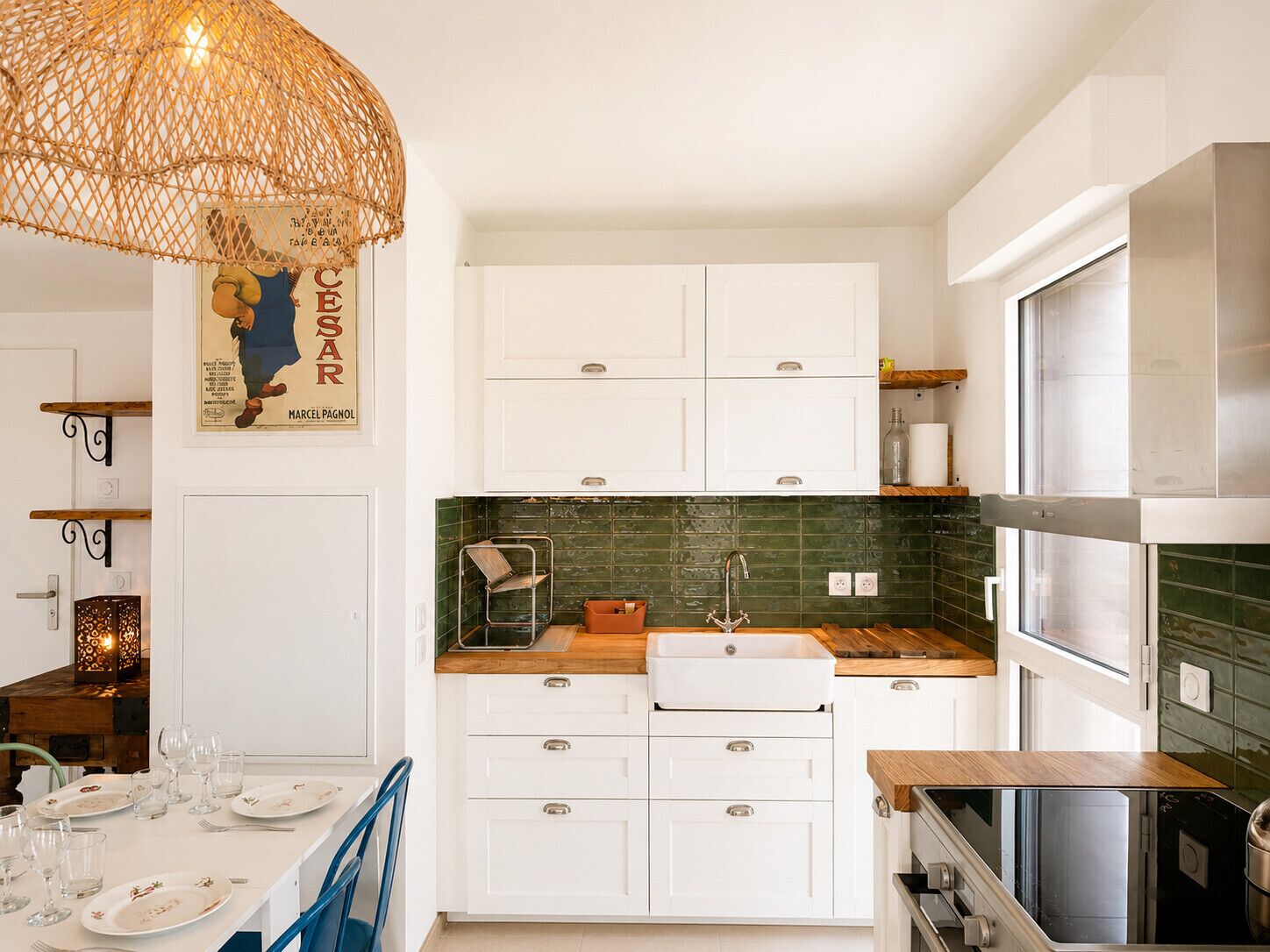 A kitchen with white cabinets, a green backsplash, a wooden countertop, and a hanging light fixture.