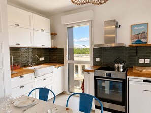 Eine moderne Küche mit weißen Schränken, einer schwarzen Fliesenspiegel und einem Edelstahlherd sowie einem Backofen.