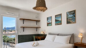 Ein Schlafzimmer mit einem Bett, zwei Wandregalen, einem Tisch mit Stuhl und drei gerahmten Bildern.