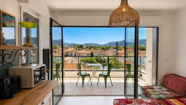 Eine moderne Wohnung mit Balkon, einer Küchenzeile und Blick auf die Stadt.