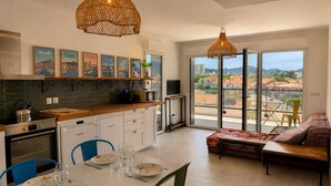 Eine moderne Küche mit Essbereich, großen Fenstern und einem Balkon mit Aussicht.