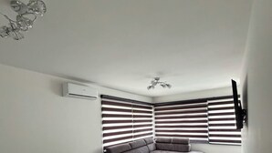 Una sala de estar moderna con un sofá modular, una mesa de comedor con sillas, una mesita redonda y un televisor montado en la pared.