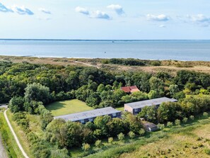 Luchtbeeld van een pand met twee gebouwen, omgeven door weelderige begroeiing en een kustlijn.