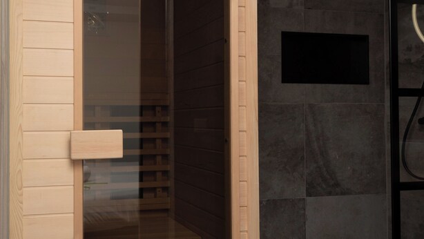 A modern bathroom with a glass enclosure, wooden paneling, and a black sink. - Bomont ZandStrand by Interhome (Renesse)
