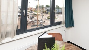 A room with a large window, a table with a book, and a chair. - Bomont ZandStrand by Interhome (Renesse)