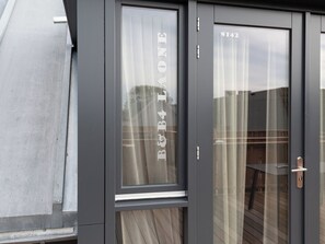 A modern building entrance with a glass door, a metal handle, and a number 'S142' on the glass. - Bomont ZeeGolf by Interhome (Renesse)