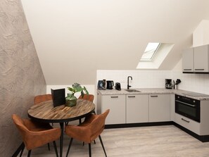A modern kitchen with a skylight, a dining table with chairs, and a coffee maker. - Bomont ZeeGolf by Interhome (Renesse)