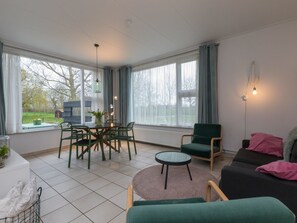 Een moderne woonkamer met een eethoek, grote ramen en een gezellige zithoek.