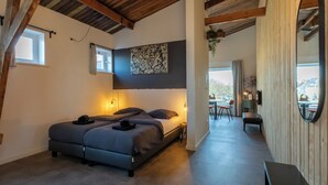 Ein Schlafzimmer mit zwei Betten, Holzboden, einem großen Spiegel und Blick ins Freie.